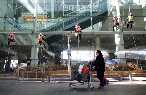 인천공항 환경미화 요원들이 밧줄에 몸을 의지한 채 여객터미널 외벽 유리창에 쌓인 먼지를 닦아내고 있다.