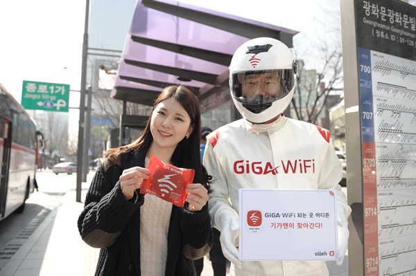 KT 모델이 GiGA WiFi가 제공되는 광화문 버스정류장에서 ‘기가맨’과 함께 기가 와이파이를 들고 포즈를 취하고 있다. (사진=KT 제공)