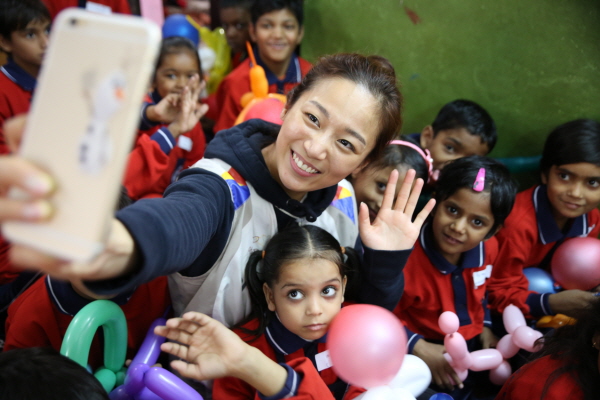 아시아나항공 직원이 지난 25일 인도 뉴델리에서 빈민층 아동을 위한 봉사활동을 하며 현지 아동들이 함께 기념 촬영을 하고 있다. <사진=아시아나항공>