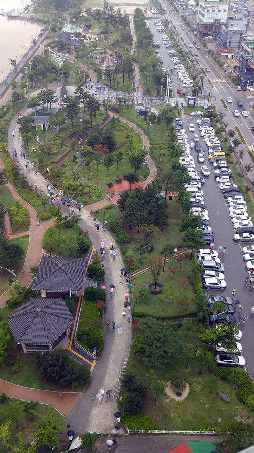 지난 7월 ‘포켓몬고’ 게임유저들이 속초 청초호 유원지 엑스포 공원을 찾아 우산을 쓰거나 비옷을 입은 채 산책로를 누비며 게임을 즐기고 있다. <사진=연합>