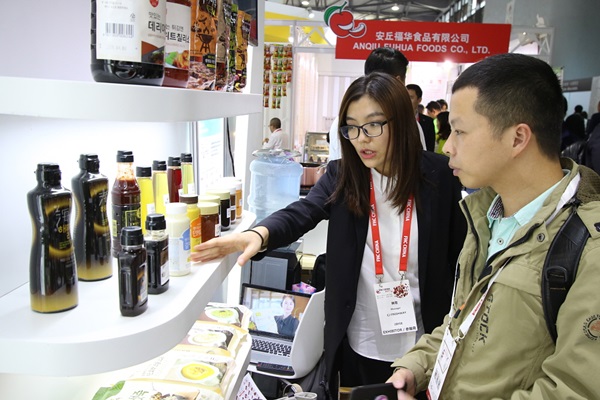 CJ프레시웨이 담당자가 ‘상해 식품박람회’에서 소스 상품에 대해 중국 바이어와 상담하고 있다. <사진=CJ프레시웨이>