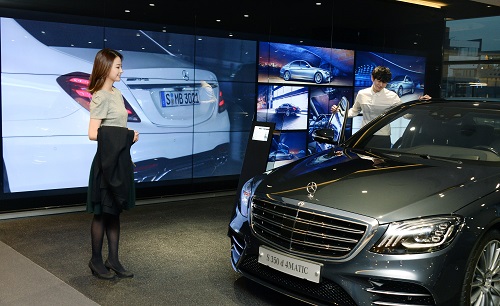 LG전자 모델들이 LCD 사이니지 18대를 이어 붙인 비디오월 앞에서 차량을 살펴보고 있다. <사진=LG전자>