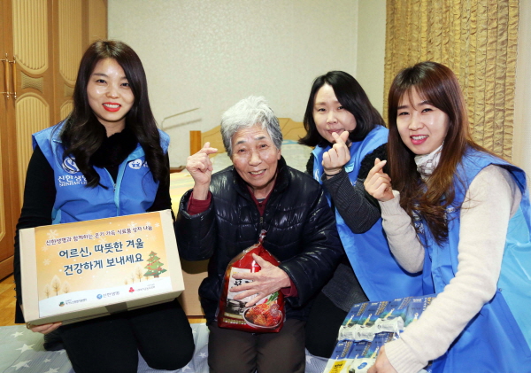 신한생명 자원봉사자들이 서울 강북구 수유동에 위치한 독거어르신 가정에 방문해 겨울나기 식료품이 담긴 바구니를 전달하고 기념촬영을 하고 있다.<사진=신한생명>