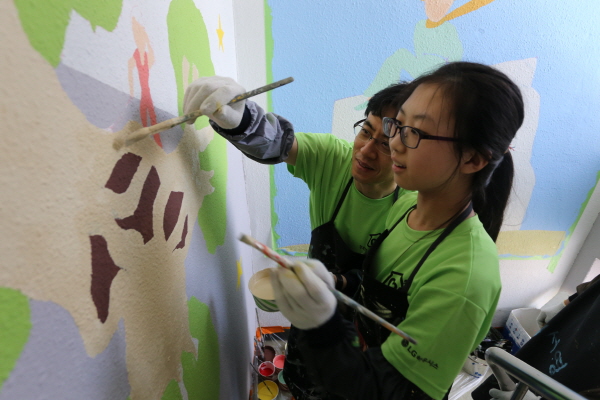 LG하우시스 직원과 자녀가 26일 서울 동대문구 이문동에 위치한 행복한 지역아동센터에서 계단 벽면에 벽화를 그리고 있다.  