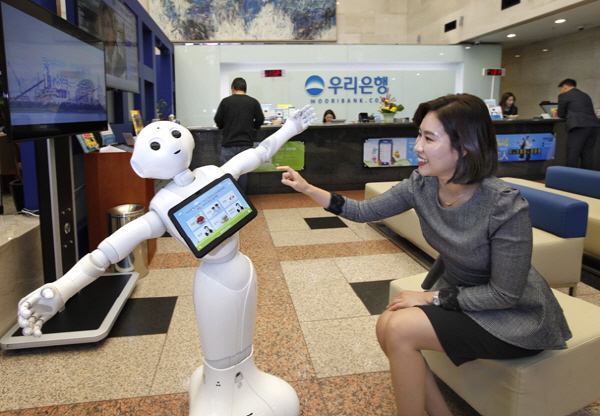 우리은행 직원이 서울에 있는 본사에서 있는 국내 최초 인공지능(AI) 기반 감정인식 로봇행원 '페퍼'를 작동시키고 있다.<사진=우리은행>