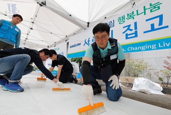 15일 서울시 용산구 해오름빌에서 박상신 대림산업 대표(우측 첫번째)가 도배작업에 사용할 벽지에 풀칠을 하고 있다. <사진=대림산업>