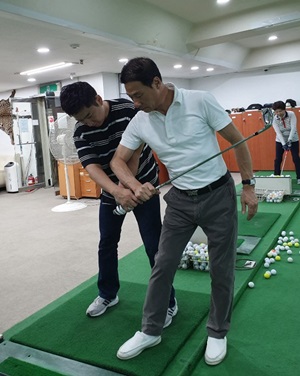속성 골프레슨의 달인으로 불리는 박종우 프로(사진 오른쪽)가 골프 레슨 도중 회원의 스윙 자세를 교정해주고 있다.