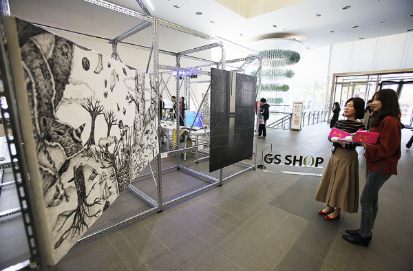 시민들이 서울 영등포구 당산동 GS홈쇼핑 본사 1층에서 열린 전시회 ‘세상의 중심에서展’에 전시된 작품을 관람하고 있다. 