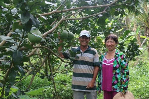 베트남 낙후농촌지역인 번째성의 농민 부부가 교보생명으로부터 지원 받은 자몽나무 열매를 보며 환하게 웃고 있다.<사진=교보생명>