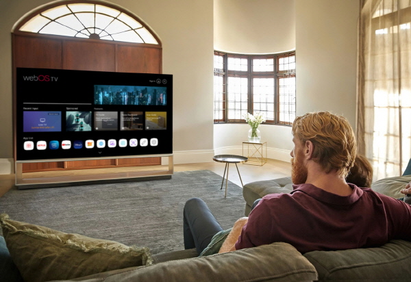 LG전자 모델이 webOS Hub를 탑재한 스마트 TV를 시청하는 모습 <사진=LG전자>