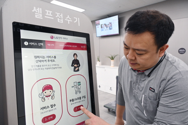 LG전자 서비스엔지니어가 서울 광진구에 위치한 LG전자 광진서비스센터에 설치된 키오스크에서 디지털휴먼의 수어 안내를 받아 서비스를 접수하는 방법을 안내하고 있다. <사진=LG전자>